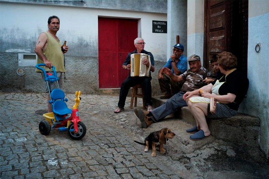 Un homme qui joue de l'accordéon dans une rue à coté d'un bar
