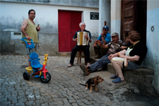 Un homme qui joue de l'accordéon dans une rue à coté d'un bar
