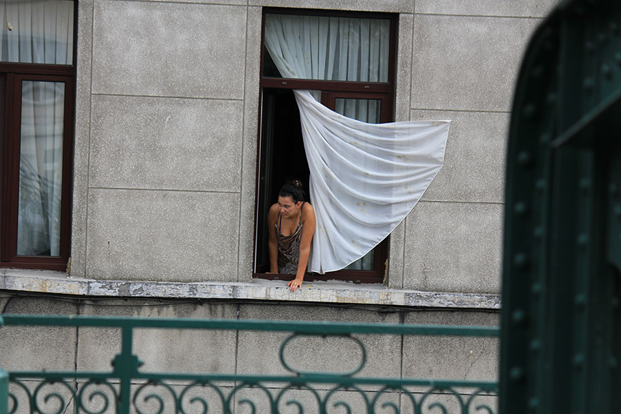 Femme à la fenêtre avec rideau blanc