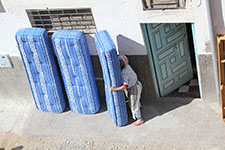 Femme avec trois matelas bleus près de sa porte