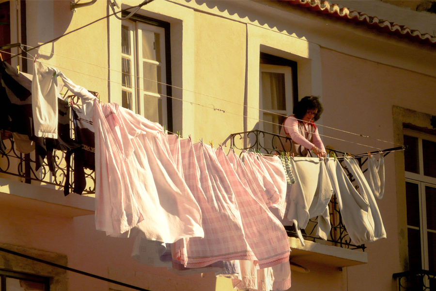 Femme qui étend du linge à sa fenêtre à Lisbonne