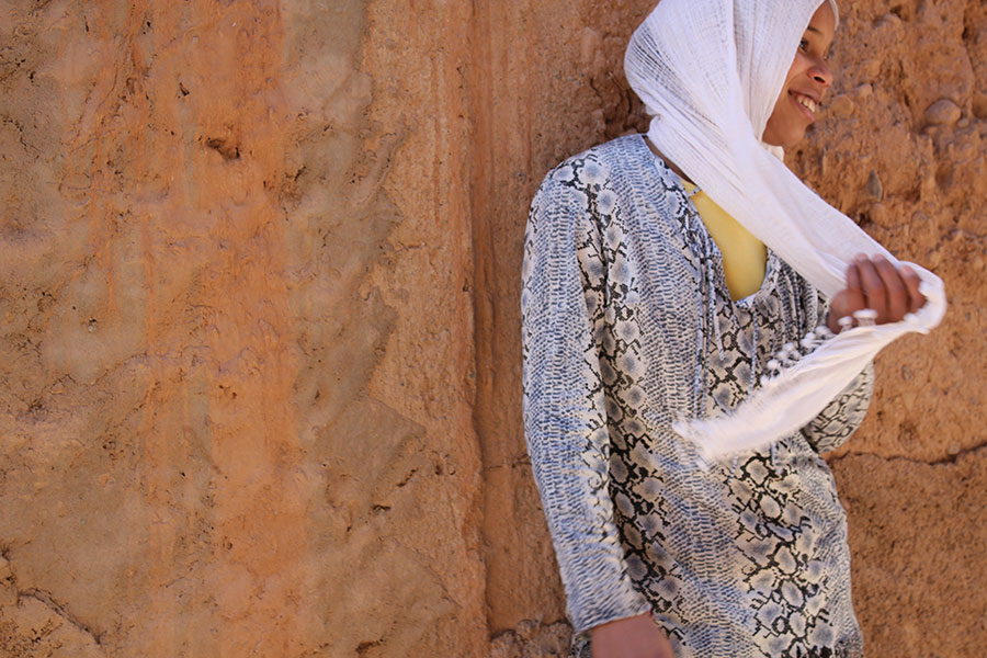 Femme souriante devant un mur ocre